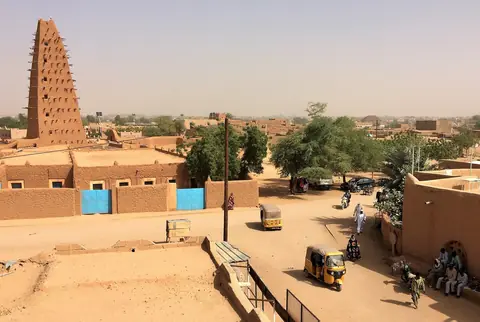 Den höga lerminareten vid stora moskén i Agadez över låga lerhus och sandiga gator