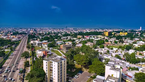 Brazzaville sett från ovan med en bred aveny, grönskande kvarter och höghus under blå himmel