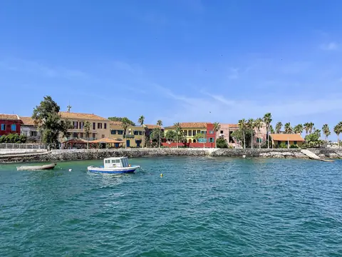 Färgglada kolonialhus och palmer vid det turkosa vattnet på ön Gorée utanför Dakar