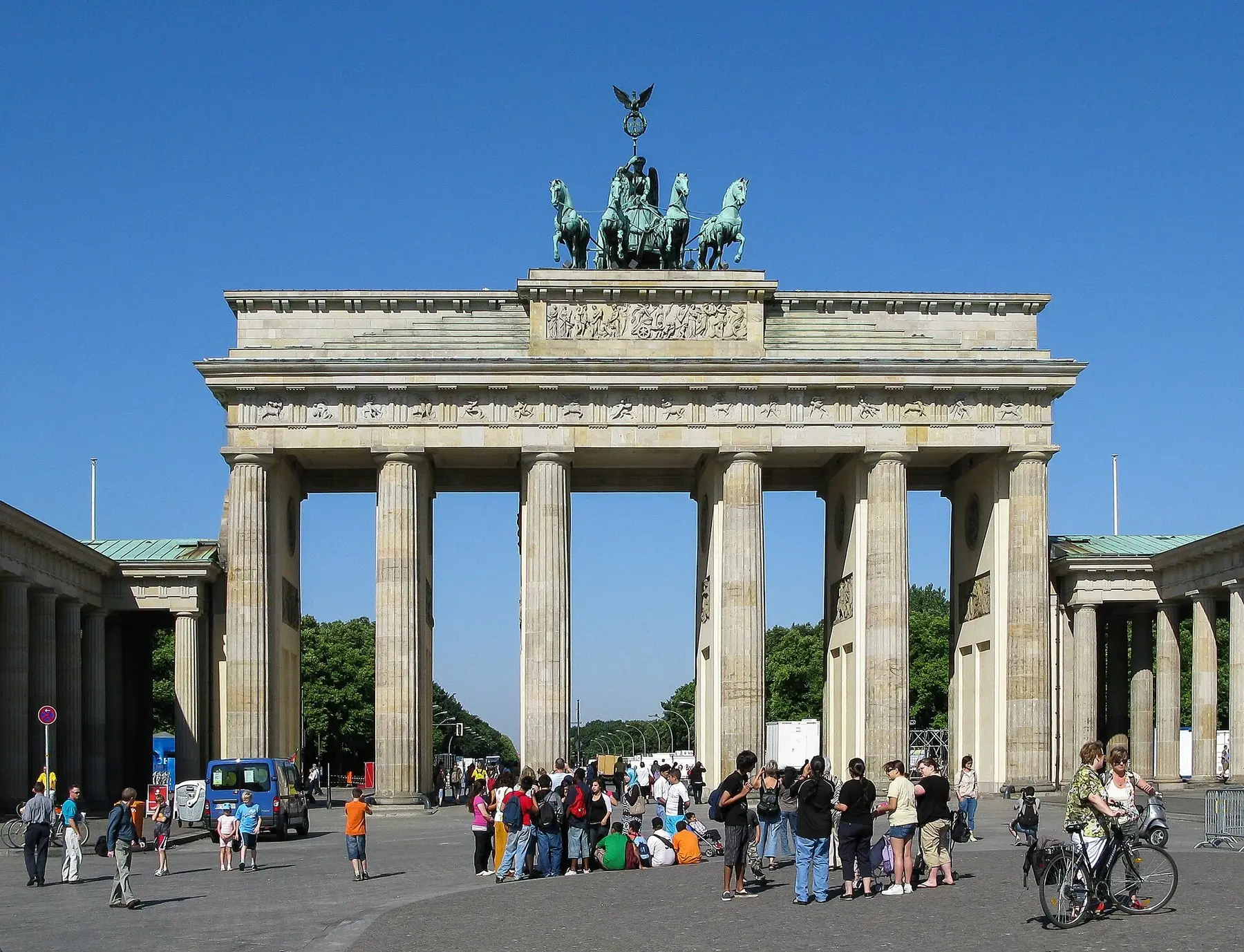Brandenburger Tor med kvadrigan på taket och turister på Pariser Platz under klarblå himmel i Berlin