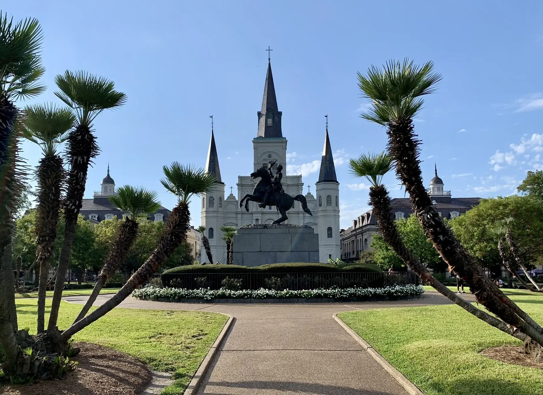 Ryttarstatyn och katedralen Saint Louis med tre spetsiga torn bakom palmer på Jackson Square i New Orleans