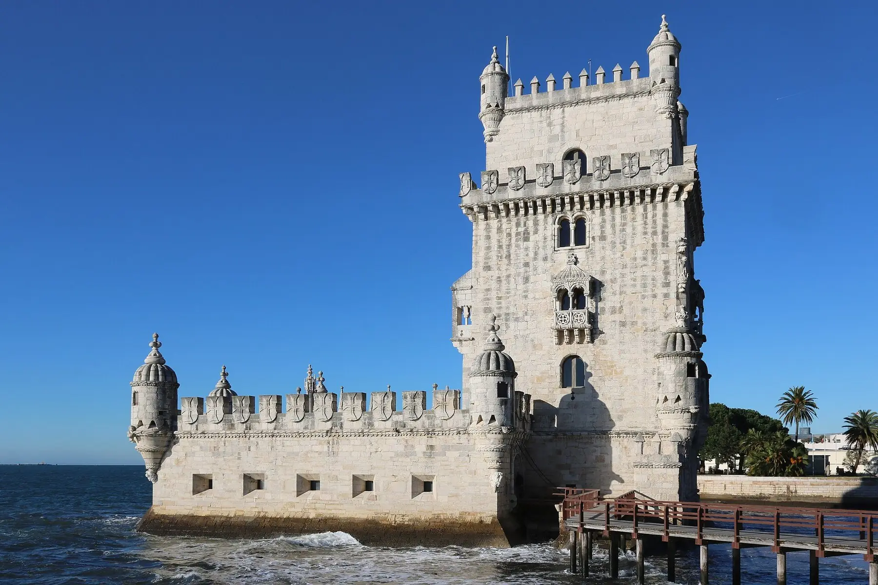 Tornet Torre de Belém i vit kalksten vid vattnet under klarblå himmel i Lissabon