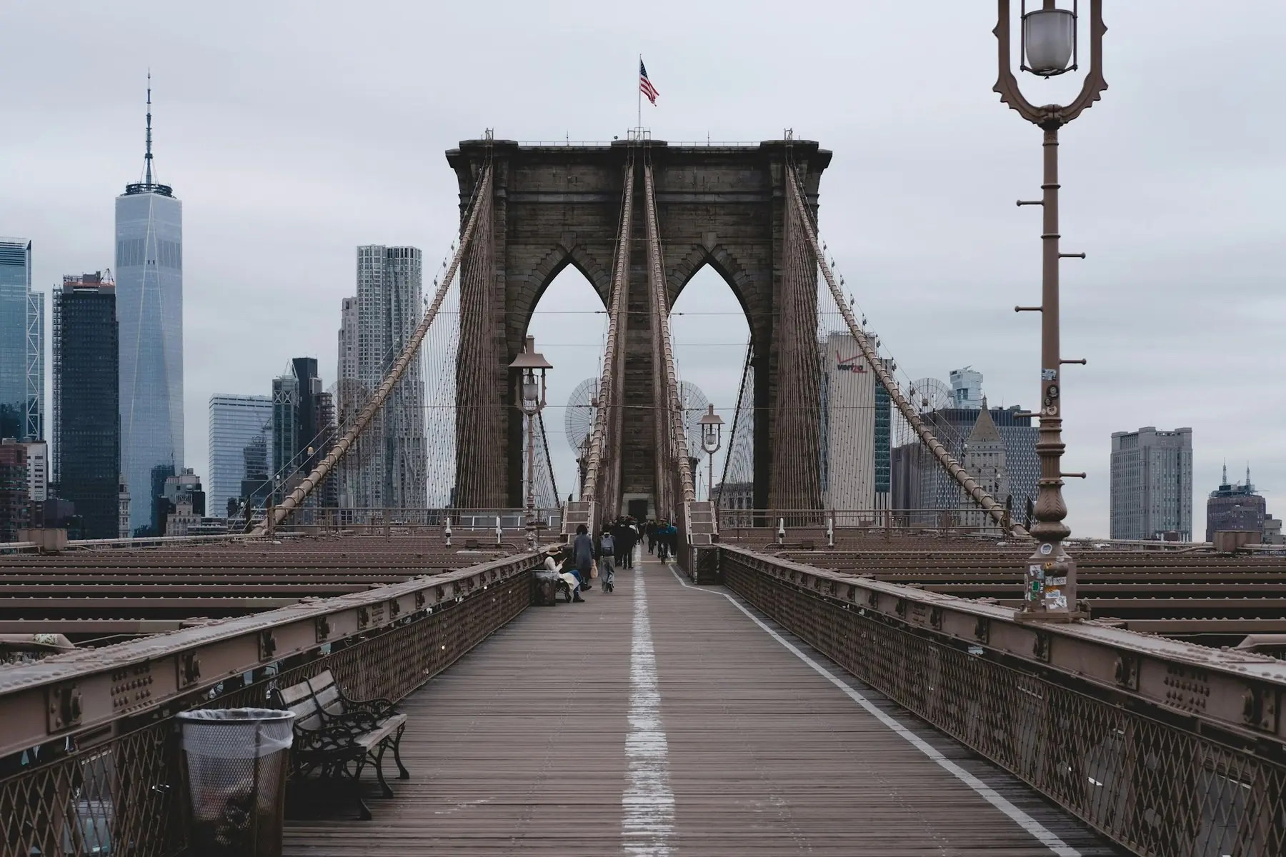 Gångbanan på Brooklyn Bridge med stenpelarens spetsbågar och Manhattans skyskrapor bakom