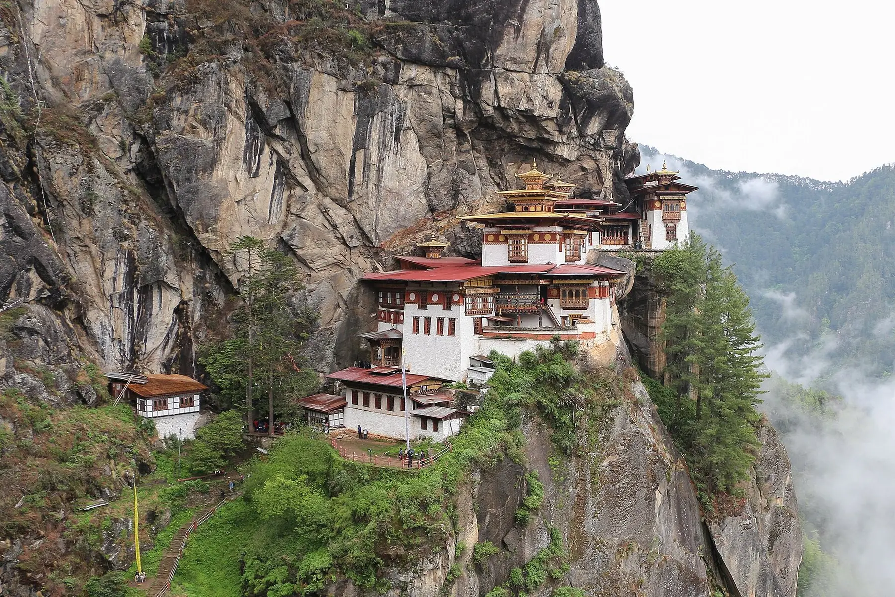 Klostret Taktsang, Tigerboet, klamrar sig fast vid en brant klippvägg ovanför skogsklädda dalar i Bhutan