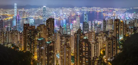 Hongkongs upplysta skyskrapor och hamnen Victoria Harbour sedda från Victoria Peak en kväll