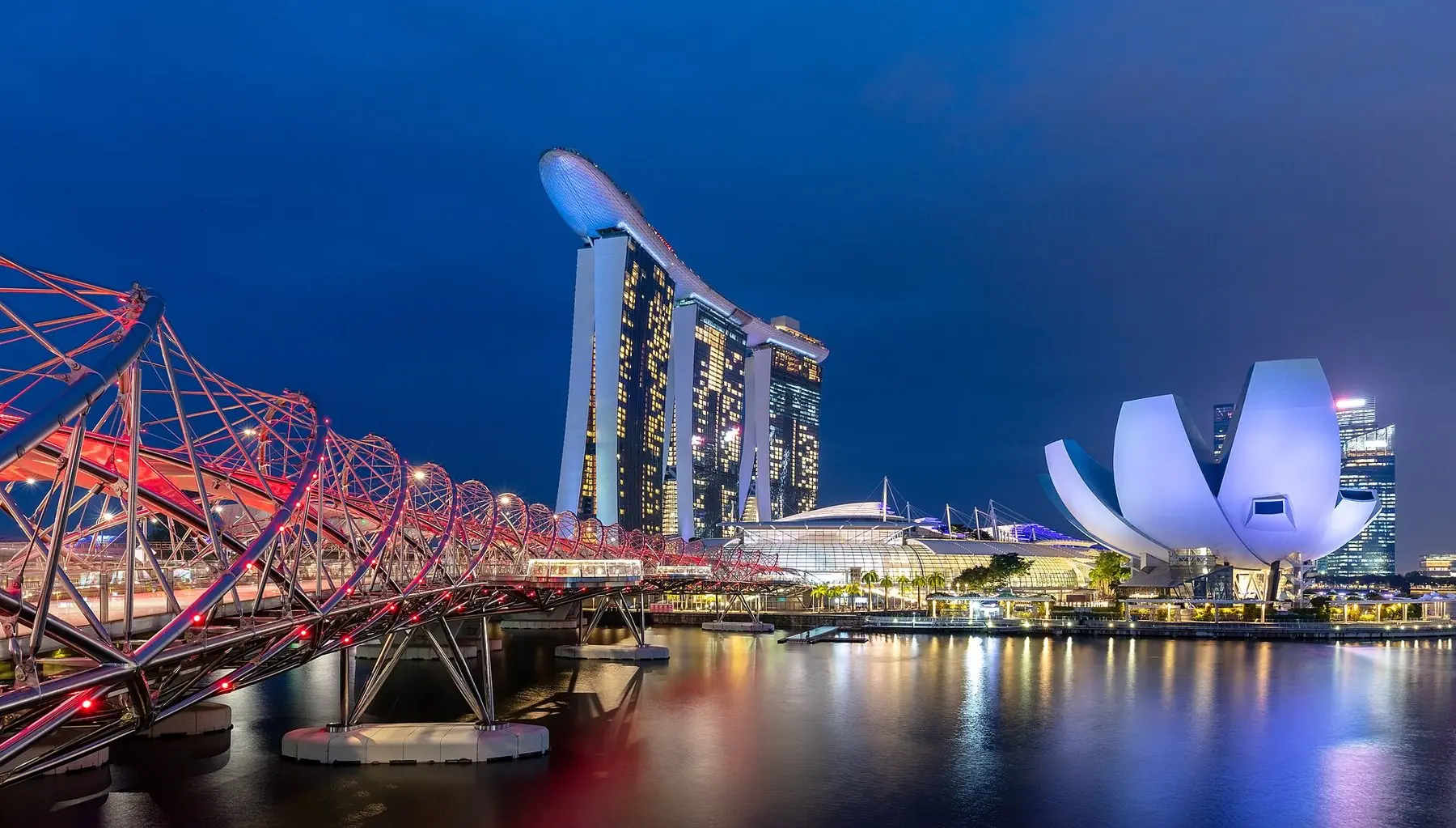 Den upplysta Helixbron, hotellet Marina Bay Sands och det lotusformade museet vid Marina Bay i blå timme