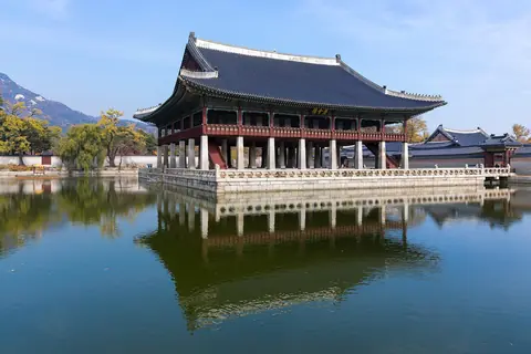 Paviljongen Gyeonghoeru med svängt tak speglar sig i en damm vid palatset Gyeongbokgung i Seoul