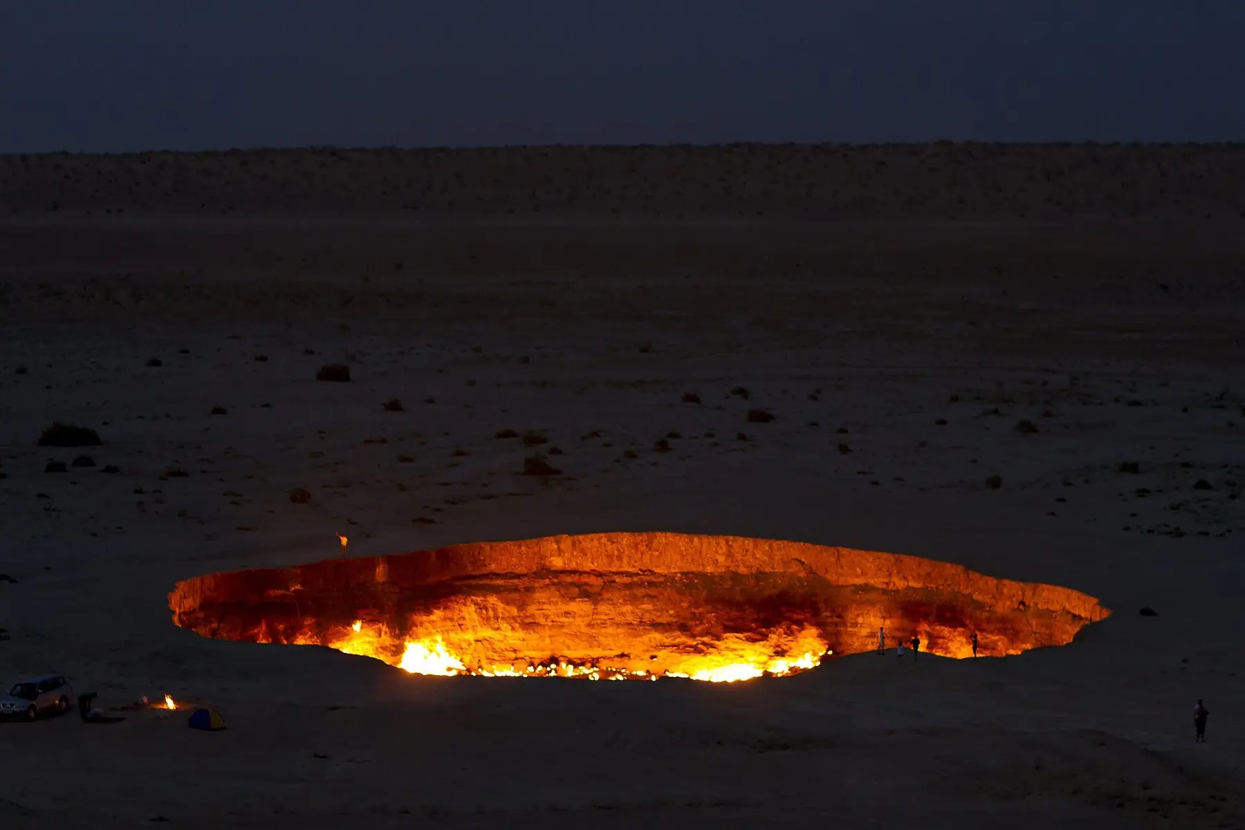 Den brinnande gaskratern Darvaza lyser orange i skymningen i Karakumöknen