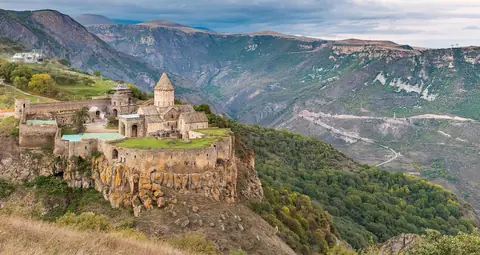 Klostret Tatev på en klippavsats ovanför en djup, grön bergsdal i södra Armenien