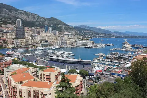 Hamnen Port Hercule full av lyxbåtar mellan tätt bebyggda sluttningar och berg i Monaco