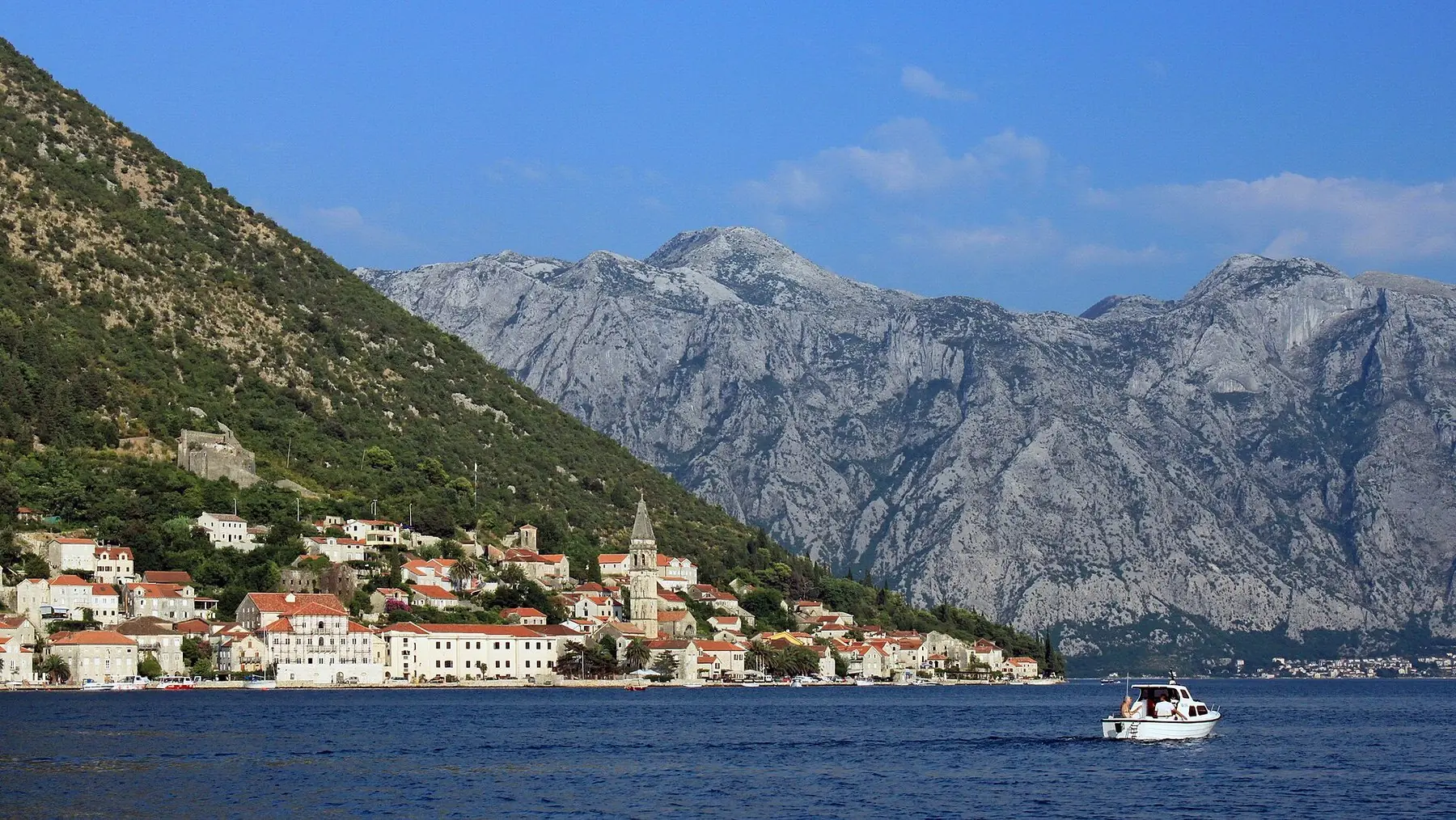 Den lilla kuststaden Perast vid vattnet under kala kalkstensberg i Kotorbukten
