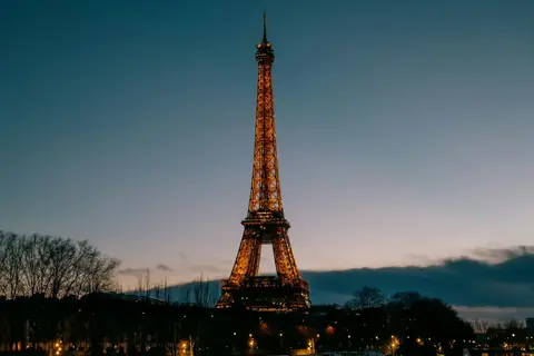Det upplysta Eiffeltornet mot kvällshimlen i Paris