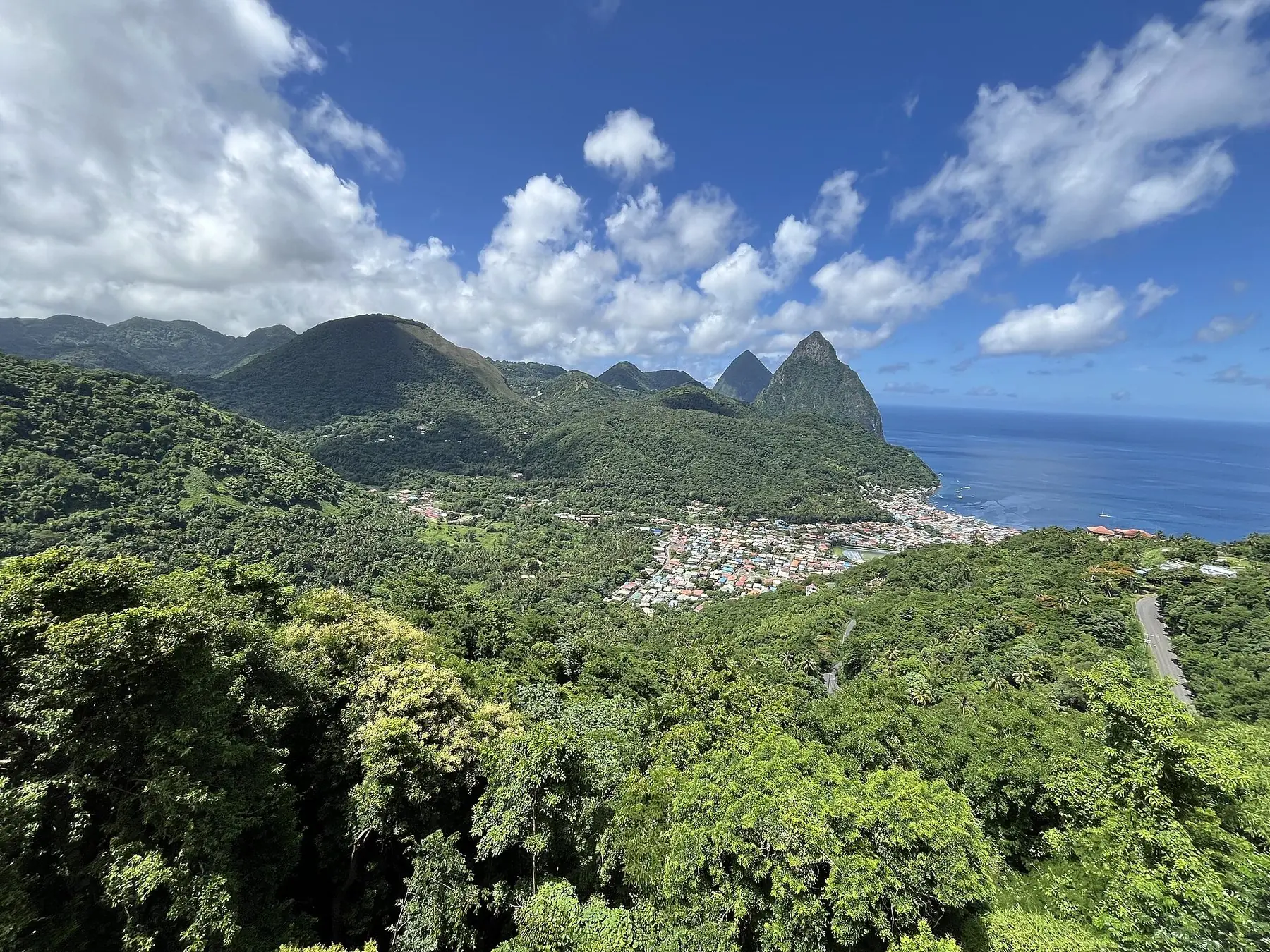 Grönskande berg, staden Soufrière och de spetsiga Pitons-topparna vid havet