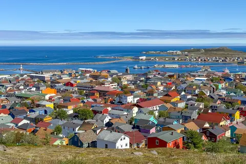 Färgglada trähus i byn Saint-Pierre med hamnen och havet i bakgrunden