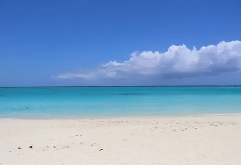 Vit sandstrand och klart turkost vatten vid Grace Bay under en blå himmel