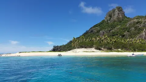 Ön Monuriki med en klippig topp, palmer och vit sandstrand vid turkost vatten i Fiji