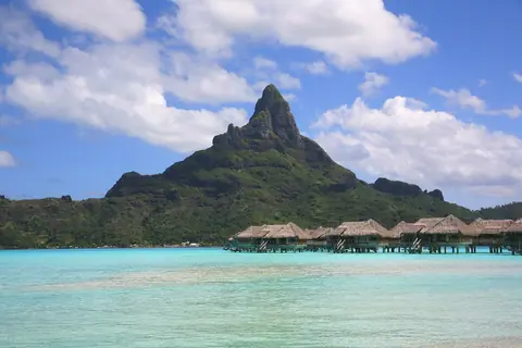 Berget Otemanu på Bora Bora ovanför en turkos lagun med överbyggda bungalower på pålar