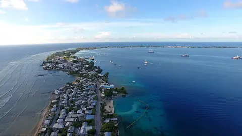 Den smala atollen Majuro med hus längs en lång landremsa mellan lagunen och havet, sett från luften