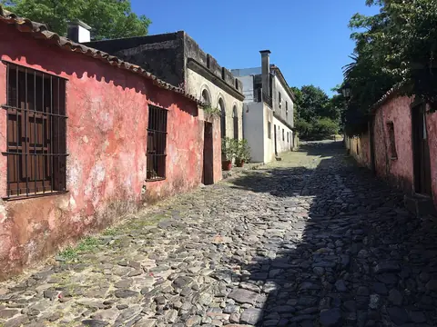 Kullerstensgatan Calle de los Suspiros med gamla rosa och vita hus i Colonia del Sacramento